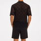 Person wearing a black patterned shirt and shorts on a white background