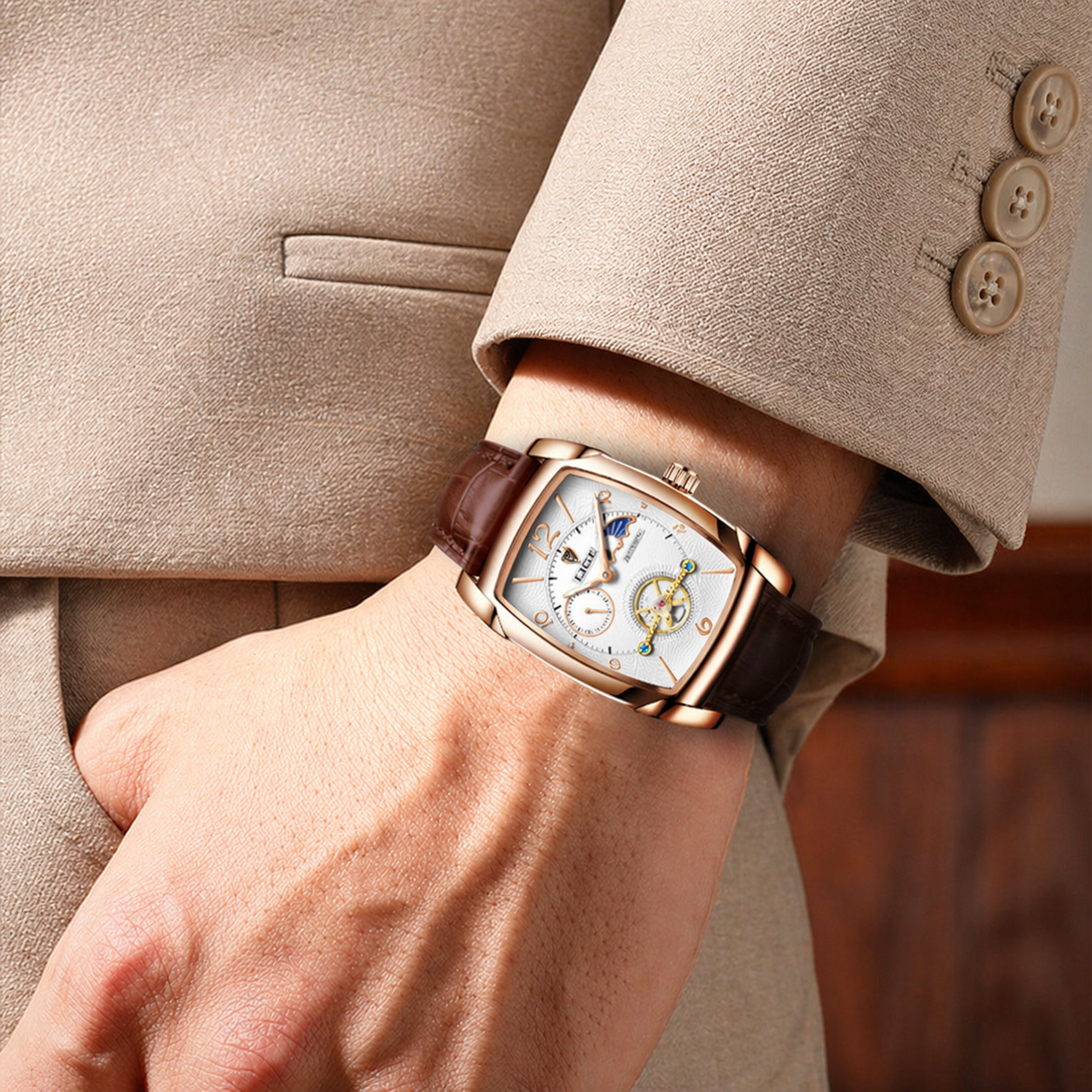 Close-up of a person wearing a luxurious watch on a beige suit background