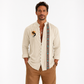 Man wearing a beige embroidered shirt with a colorful pattern on a white background