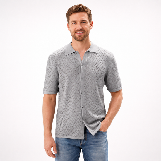 Man wearing a gray patterned shirt and blue jeans on a white background