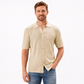 Man wearing a beige patterned shirt and blue jeans on a white background