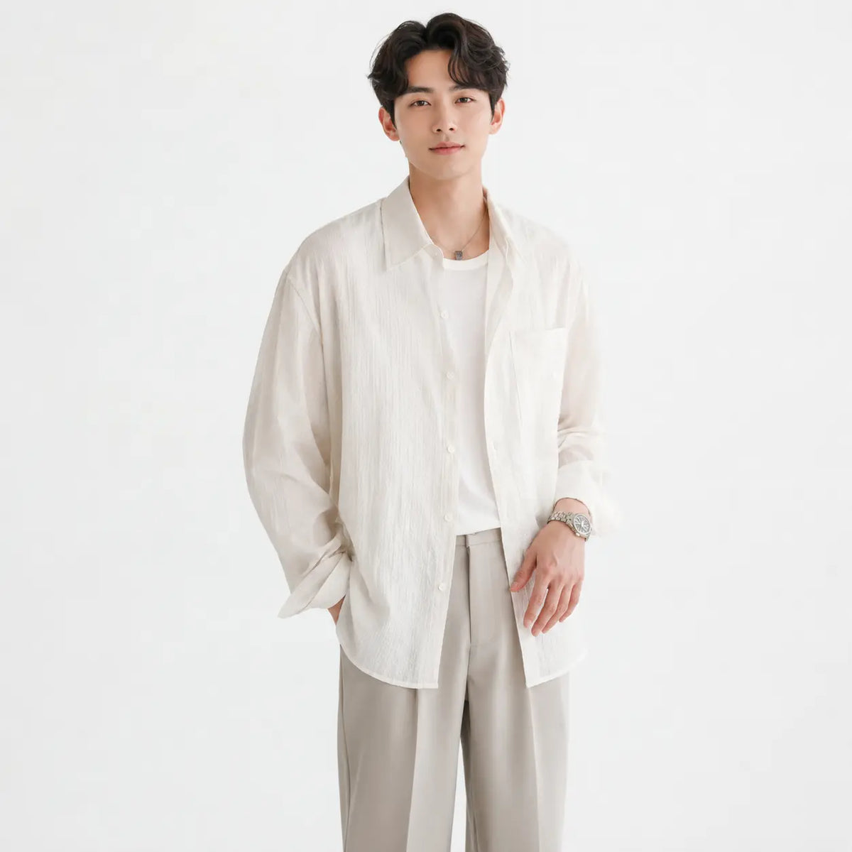 Men's linen shirt - loose fit long sleeve solid color button up in cream worn by a model with hands in pockets.