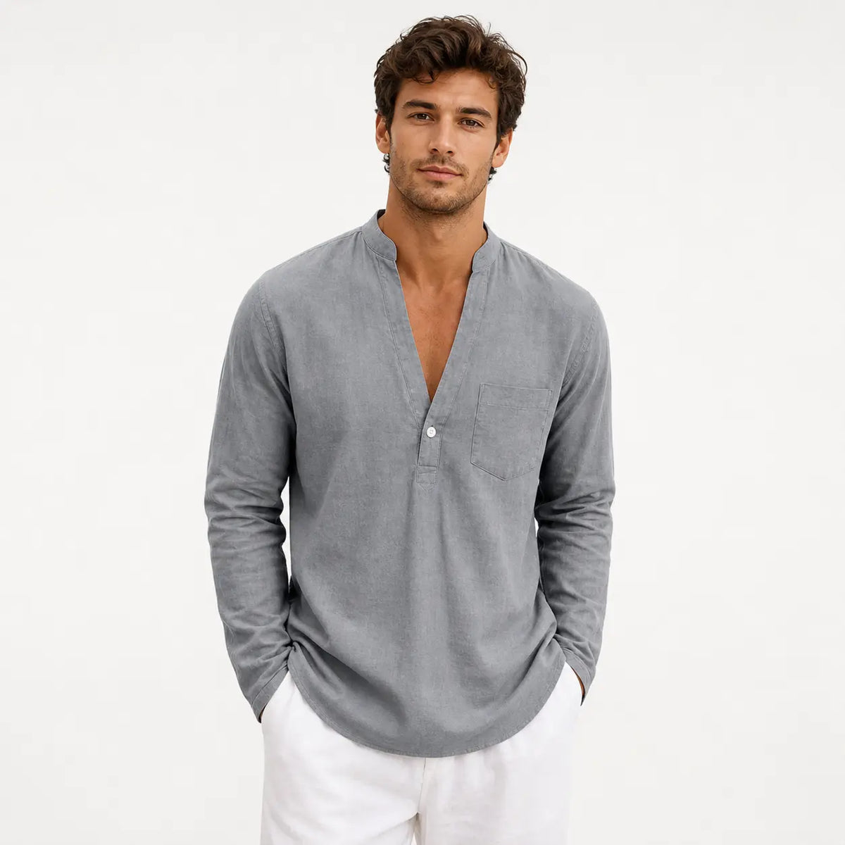 Men's linen loose fit long sleeve shirt in grey, worn by a model with hands in pockets against white background.