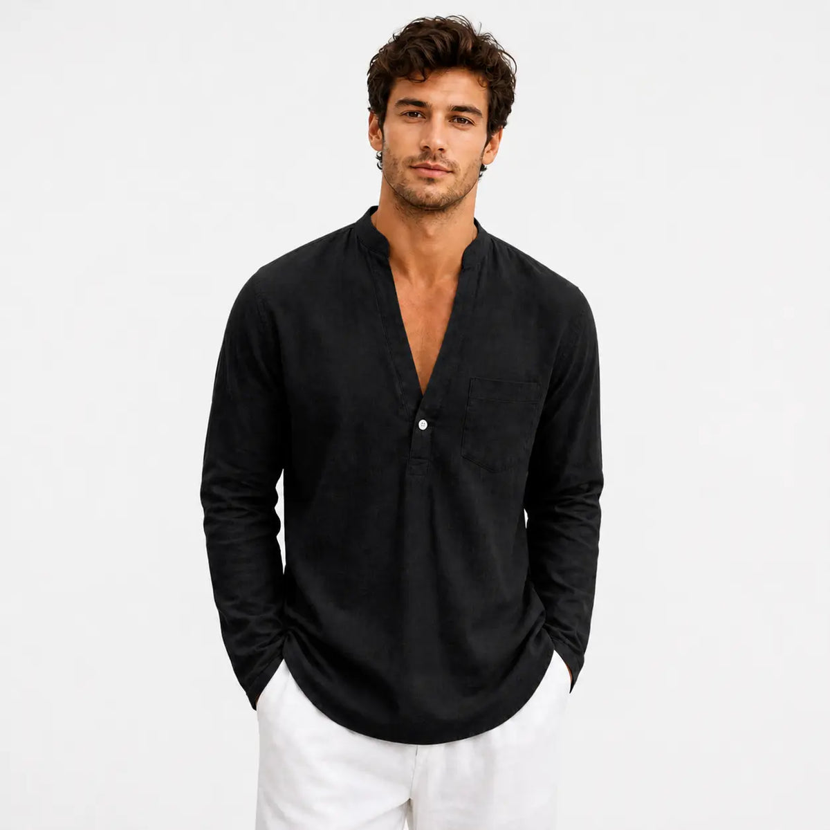 Men's linen loose fit long sleeve shirt in black, worn by a model with hands in pockets against white background.