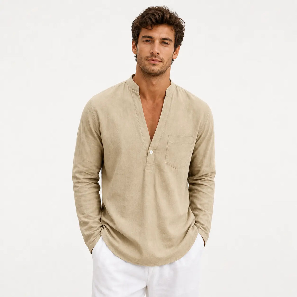 Men's linen loose fit long sleeve shirt in beige, worn by a model with hands in pockets against white background.