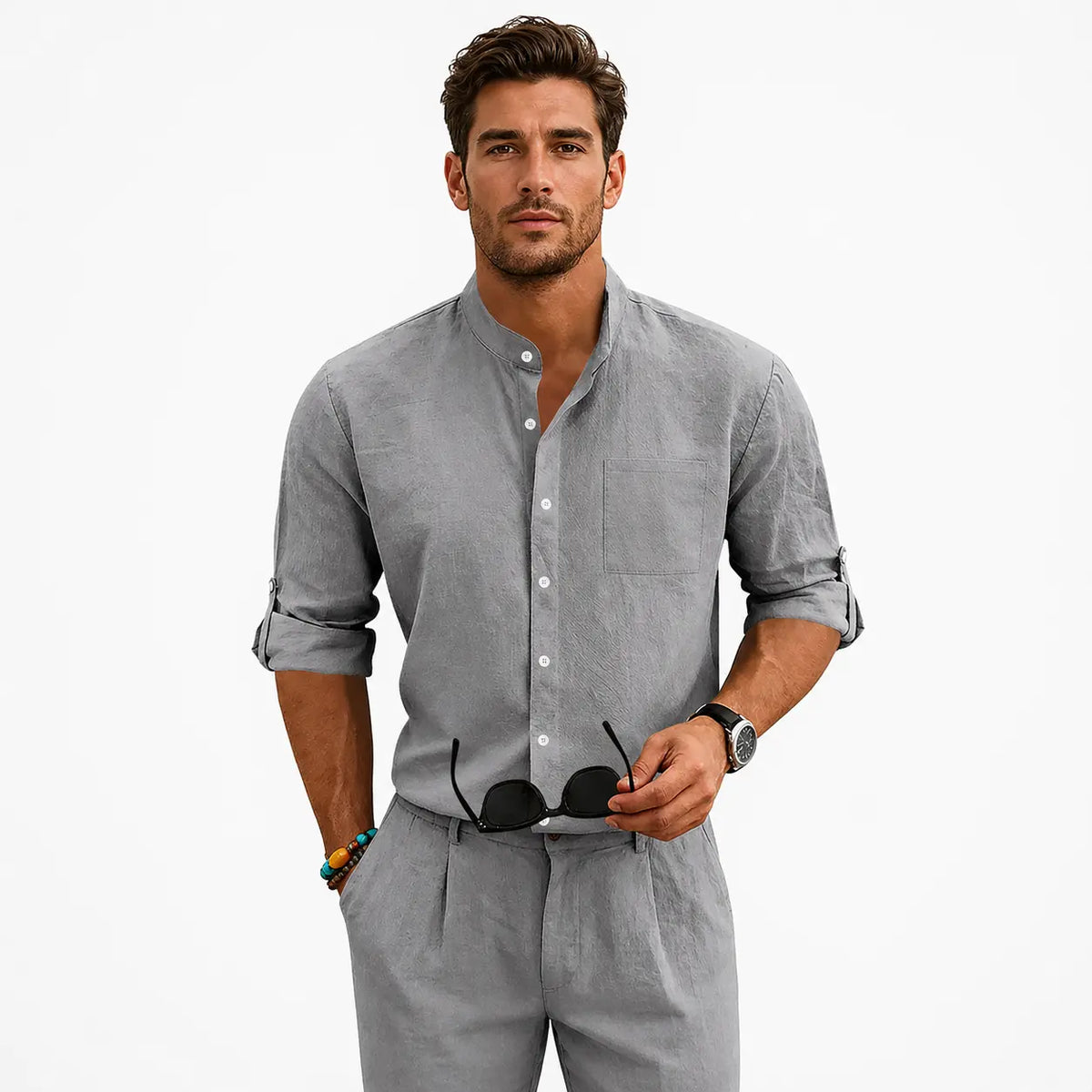 Men's linen shirt with stand-up collar in gray, worn by a model with rolled sleeves and sunglasses in hand.
