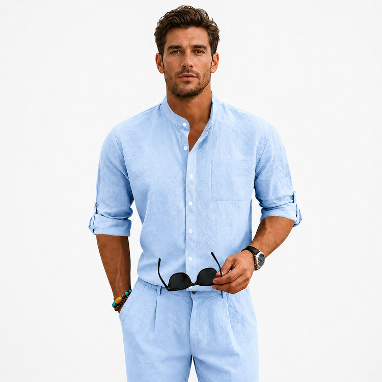 Man wearing a light blue shirt and pants holding sunglasses on a white background