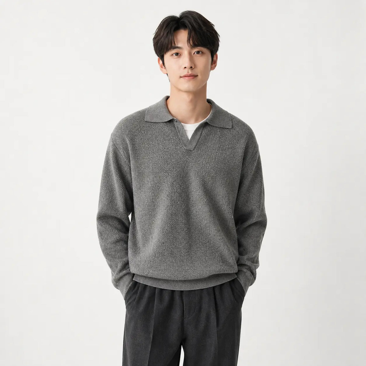 Men's slim fit polo sweater in dark gray worn by a model with hands in dark gray pants pockets against white background