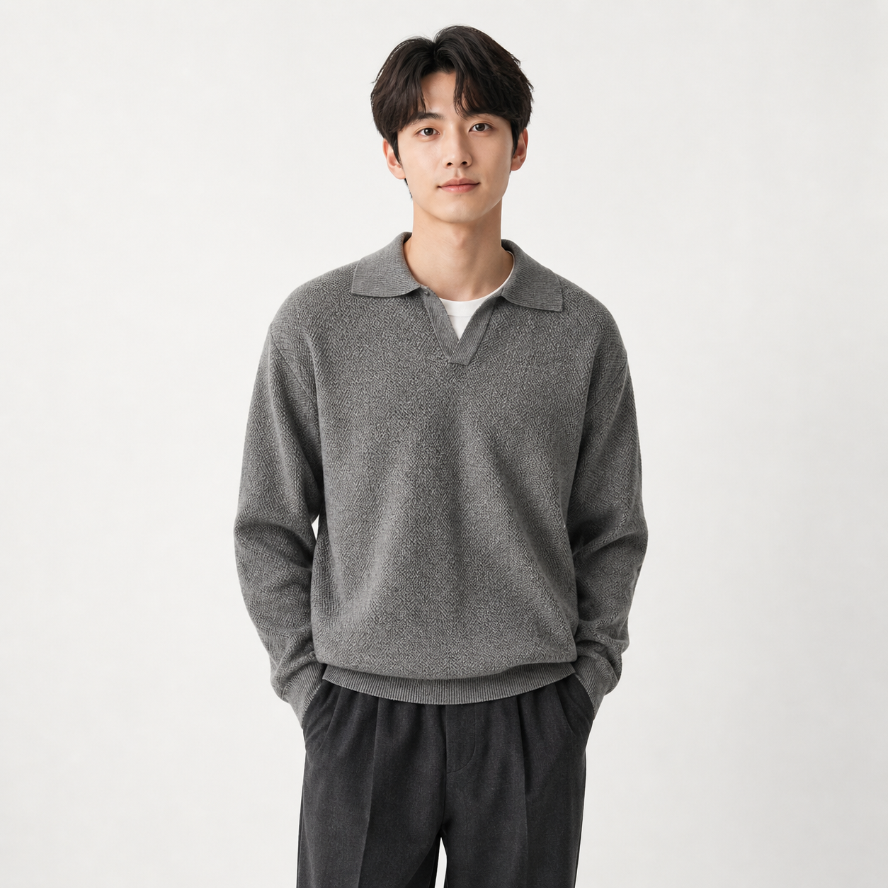 Man wearing a gray sweater and dark pants on a white background