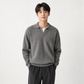 Man wearing a gray sweater and dark pants on a white background