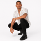 Man wearing a white patterned shirt, black pants, and black shoes on a white background