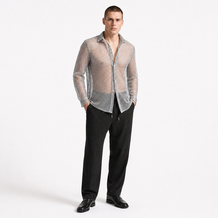Man wearing a sheer beige shirt over a patterned shirt with black pants on a white background
