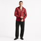 Man wearing a red patterned shirt over a black shirt with black pants on a white background