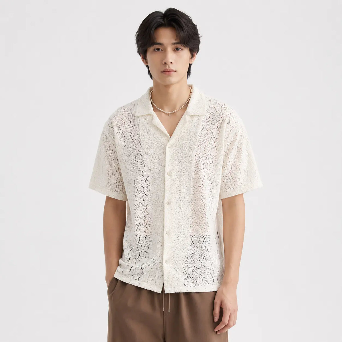 Vintage short-sleeve floral shirt for men, classic cardigan style in cream color worn by a model with pearl necklace.