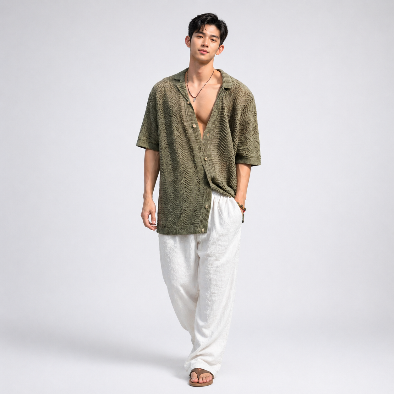 Man wearing a green knitted shirt and white pants on a plain background