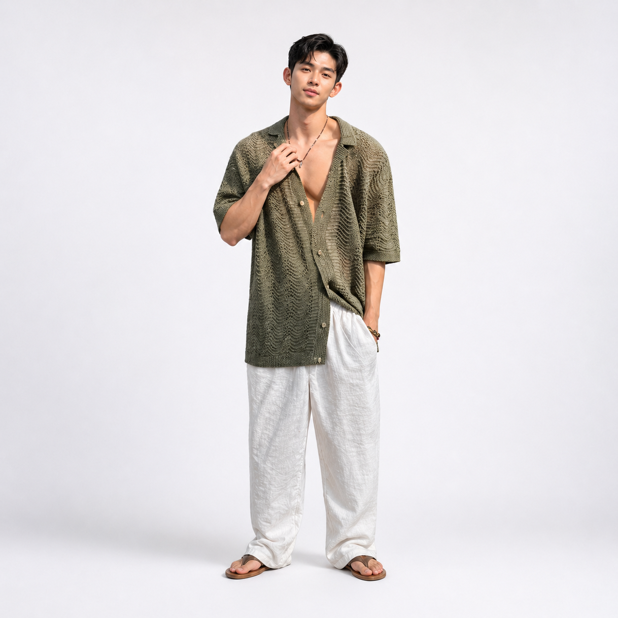 Man wearing a green textured shirt and white pants on a white background