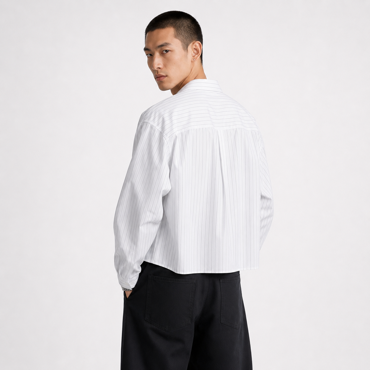 Person wearing a white button-up shirt and black pants on a white background