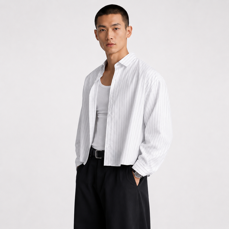 Man wearing a white striped shirt over a white tank top with black pants on a light gray background