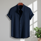 Navy blue short-sleeve shirt on a hanger with a plant in the corner