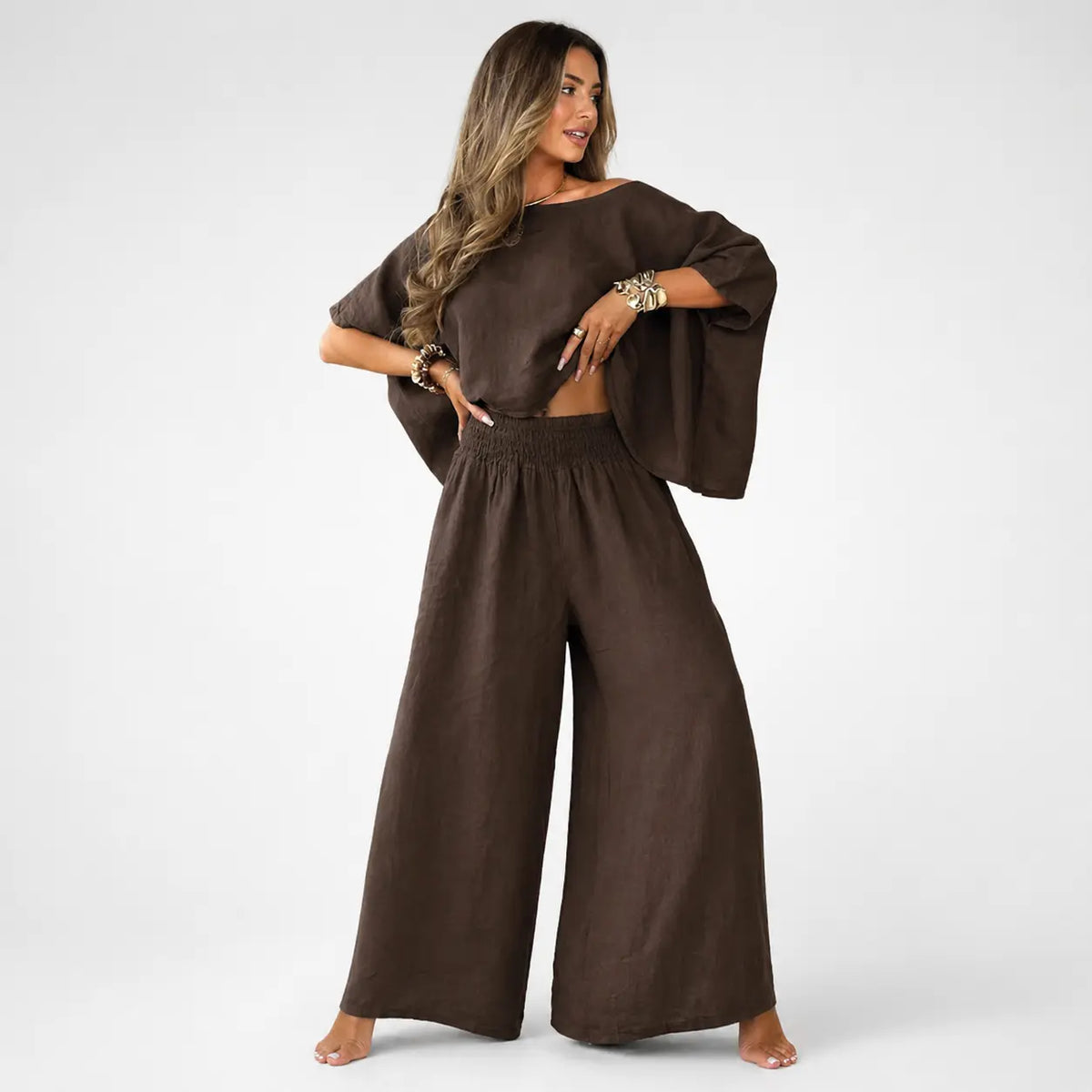Woman wearing a brown outfit with wide-leg pants and a matching top on a white background