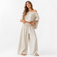 Woman wearing a beige off-shoulder top and wide-leg pants on a white background