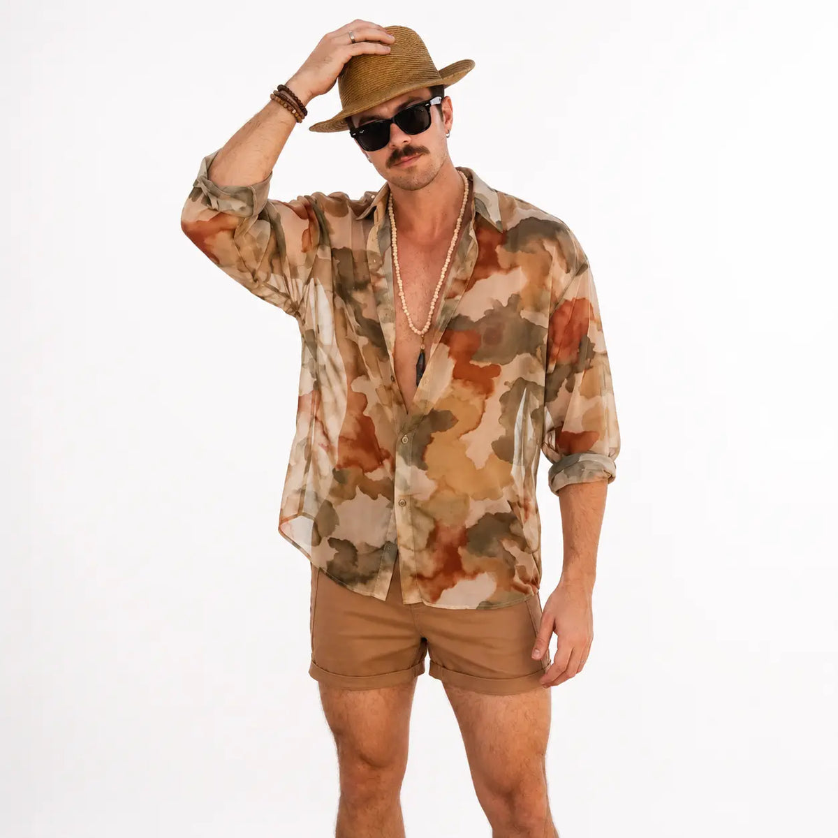 Watercolor camouflage sheer shirt, oversized variant in earthy tones, worn by a model with rolled sleeves and accessories.