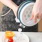 Person using a silicone mold to create ice cubes on a kitchen counter with fruits.