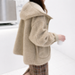Person wearing a beige sherpa jacket in a minimal indoor setting