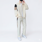 Person wearing a beige tracksuit with black accents on a white background