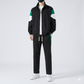 Person wearing a black and green tracksuit with white sneakers on a light gray background