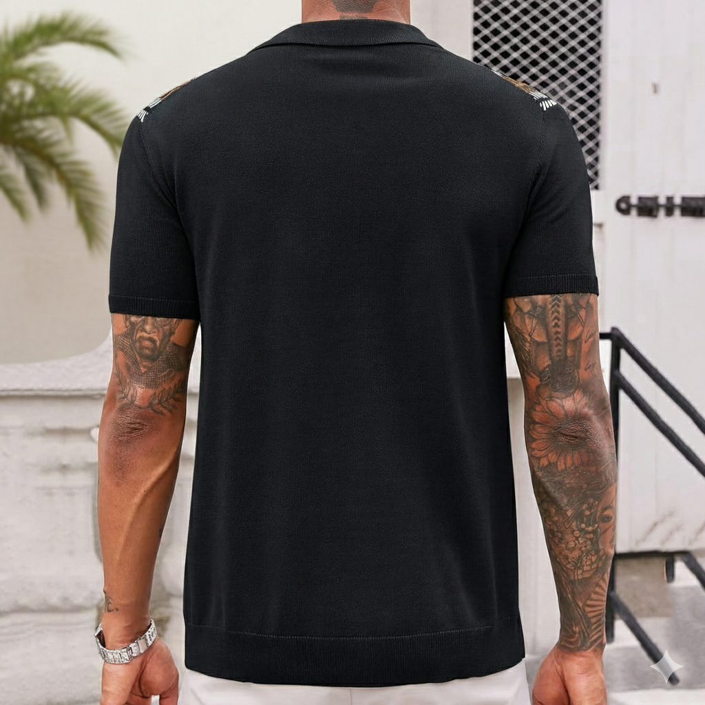 Person wearing a black polo shirt with visible tattoos on arms, standing outdoors.