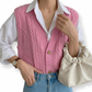 Person wearing a pink knitted vest over a white shirt with blue jeans on a white background