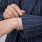 Person wearing a silver bracelet with a navy pinstripe suit
