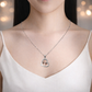 Person wearing a silver necklace with a heart-shaped pendant