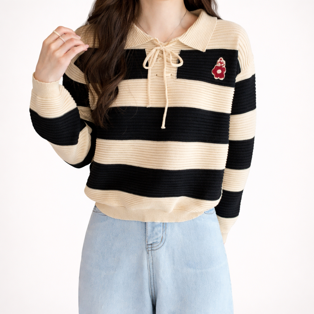 Person wearing a striped sweater with a red flower patch on a white background