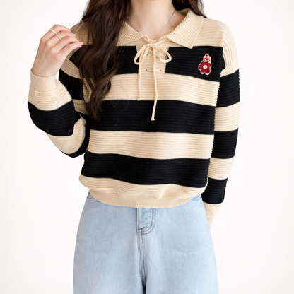 Person wearing a striped sweater with a red flower patch on a white background