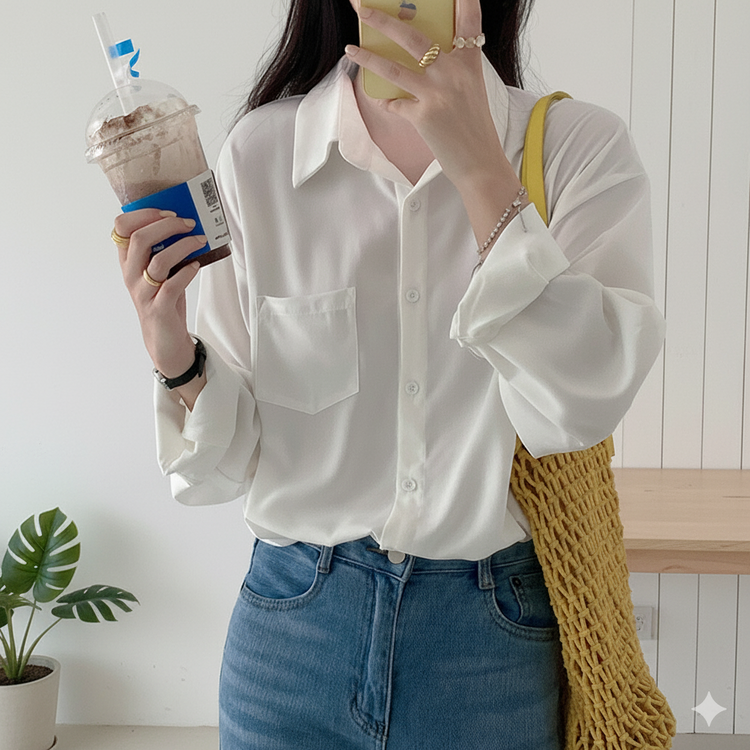 Person wearing a white shirt and blue jeans, holding a drink and a phone, with a yellow bag over their shoulder.