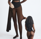 Person wearing black tights and a black bodysuit with a white background