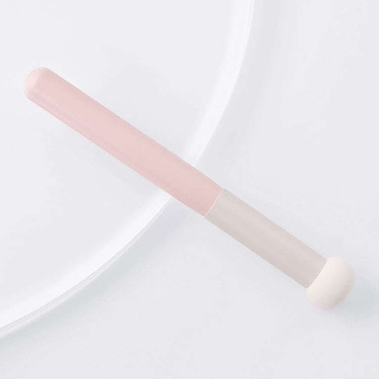 Pink makeup brush on a light gray background