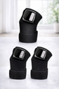 Product showcase of three identical heated knee therapy wraps arranged neatly, highlighting textured fabric and electronic control units.