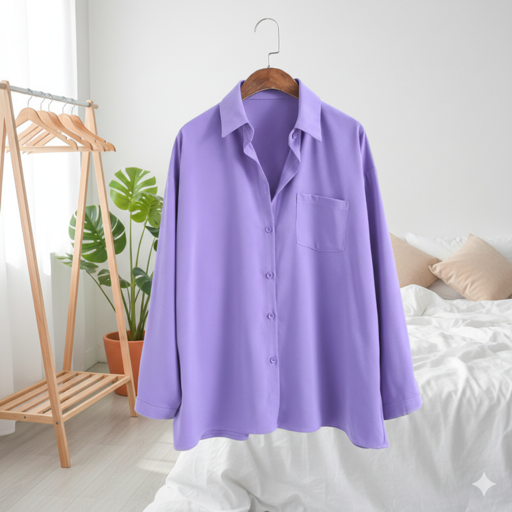 Purple shirt on a hanger against a white wall with a bed and plant in the background