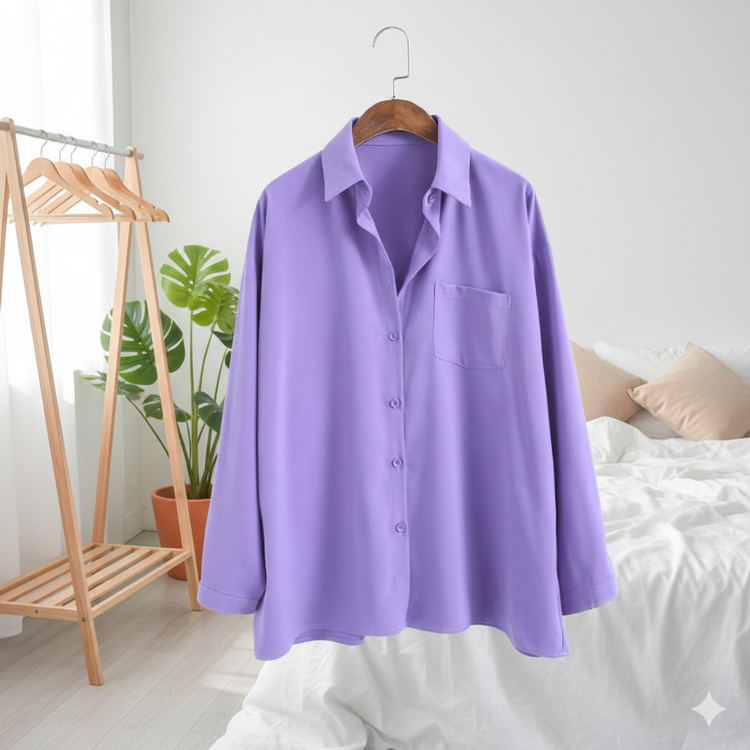 Purple shirt on a hanger against a white wall with a bed and plant in the background