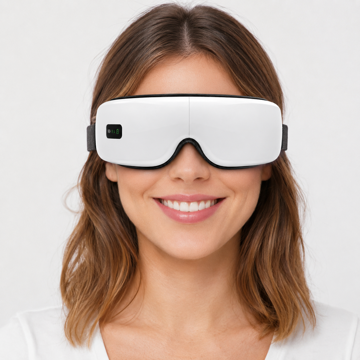 Woman wearing a white eye mask with a black strap on a plain background