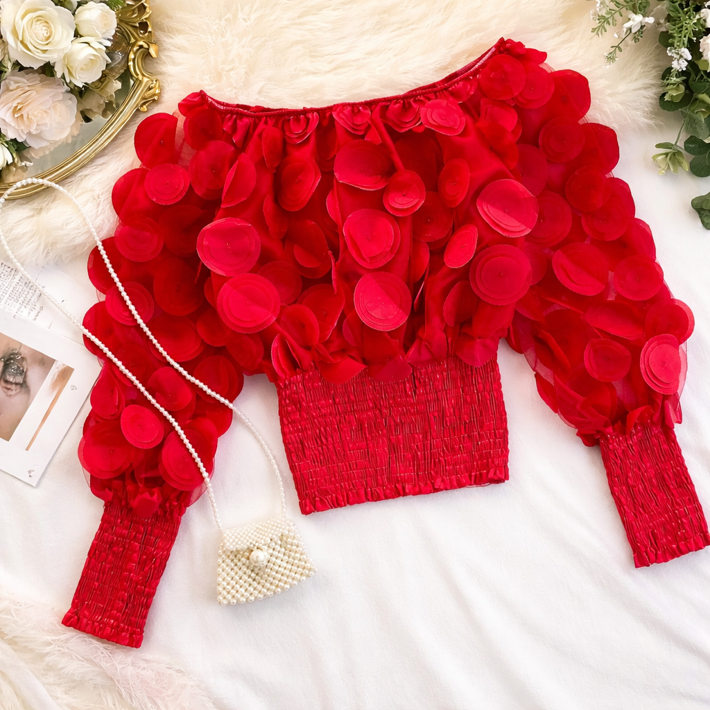 Red floral top with long sleeves on a white surface with decorative elements.