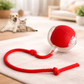 Red pet toy with a rope and ball on a light surface, with a dog and cat in the background.