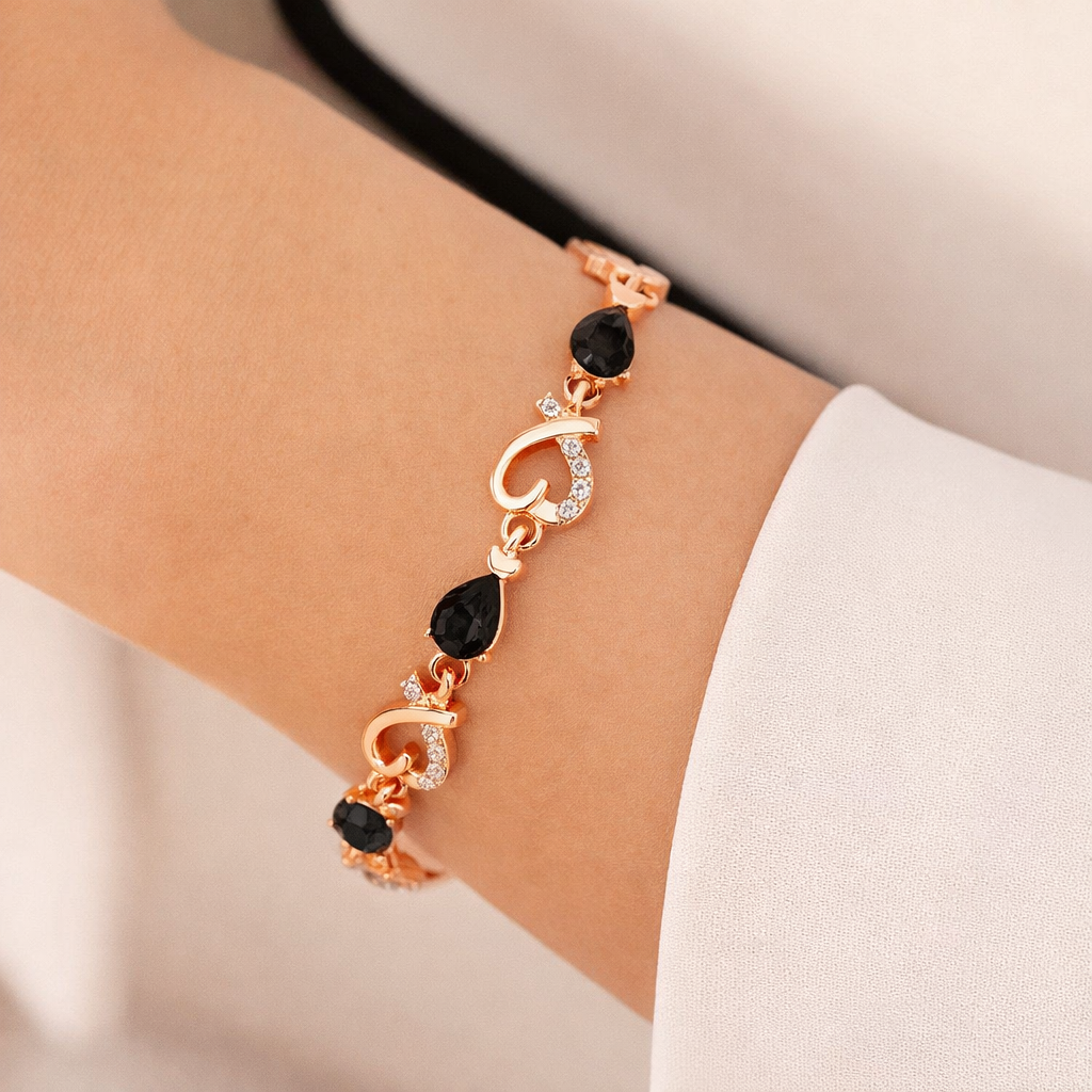 Rose gold bracelet with black gemstones on a wrist against a neutral background