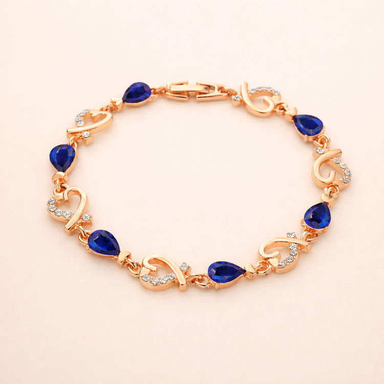 Rose gold bracelet with blue teardrop stones on a beige background