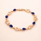 Rose gold bracelet with blue teardrop stones on a beige background