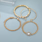 Set of gold hoop earrings and bracelets on a light blue background
