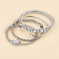 Set of silver hoop earrings and bracelets on a light blue background